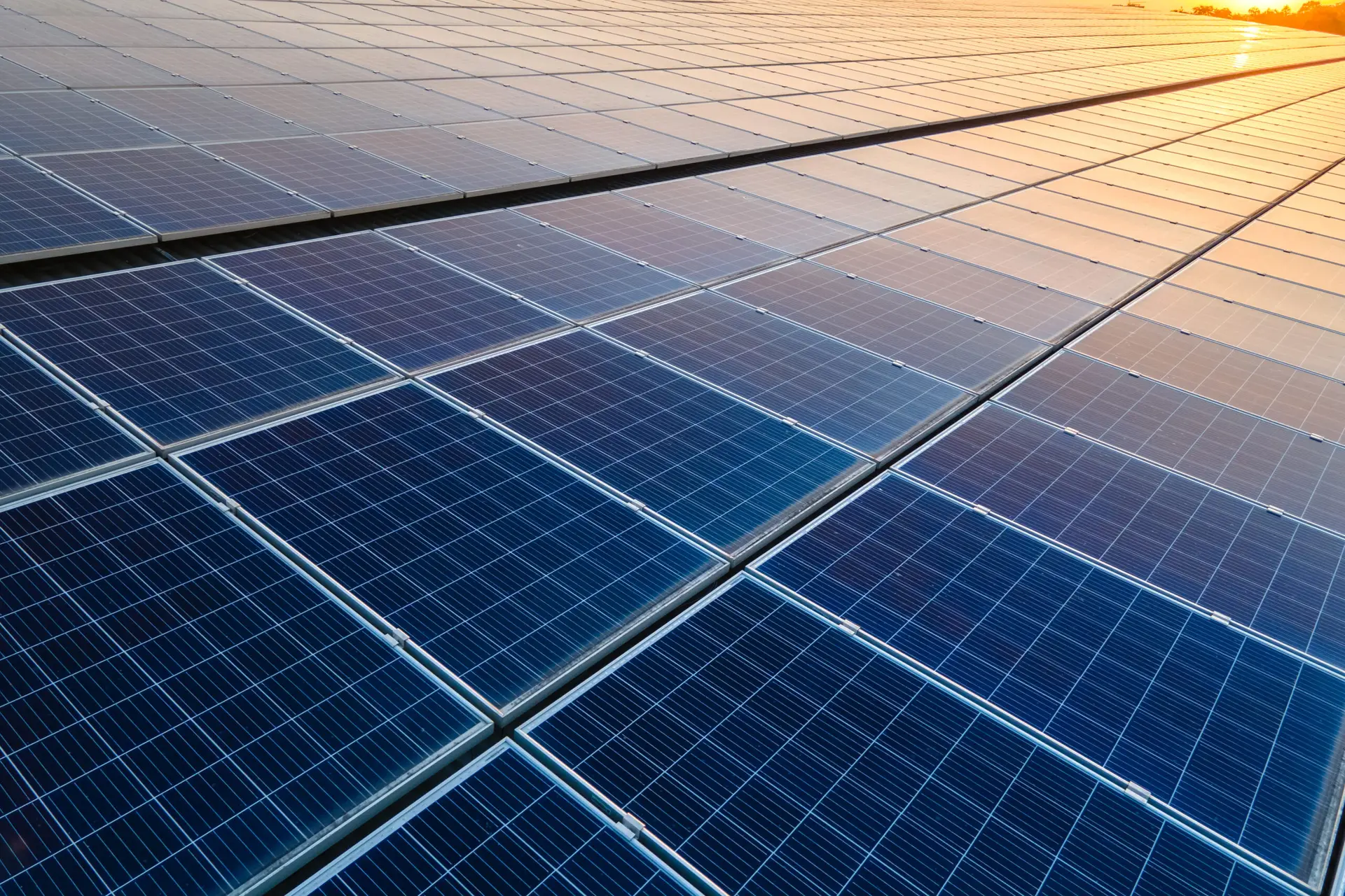 Blue photovoltaic solar panels mounted on building roof for producing clean ecological electricity at sunset. Production of renewable energy concept.
